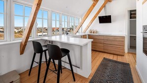 A modern kitchen with a large island, wooden beams, and a view of the outside. - 4 Star Holiday Home in Lokken (Lokken)