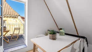 A room with a white table, two chairs, a potted plant, and a view of a building through a window. - 4 Star Holiday Home in Lokken (Lokken)