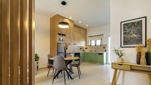 Una cocina moderna con armarios de madera, una mesa de comedor con sillas, un microondas y una lámpara colgante.