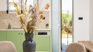 Un comedor con una mesa, sillas y un jarrón con flores secas.