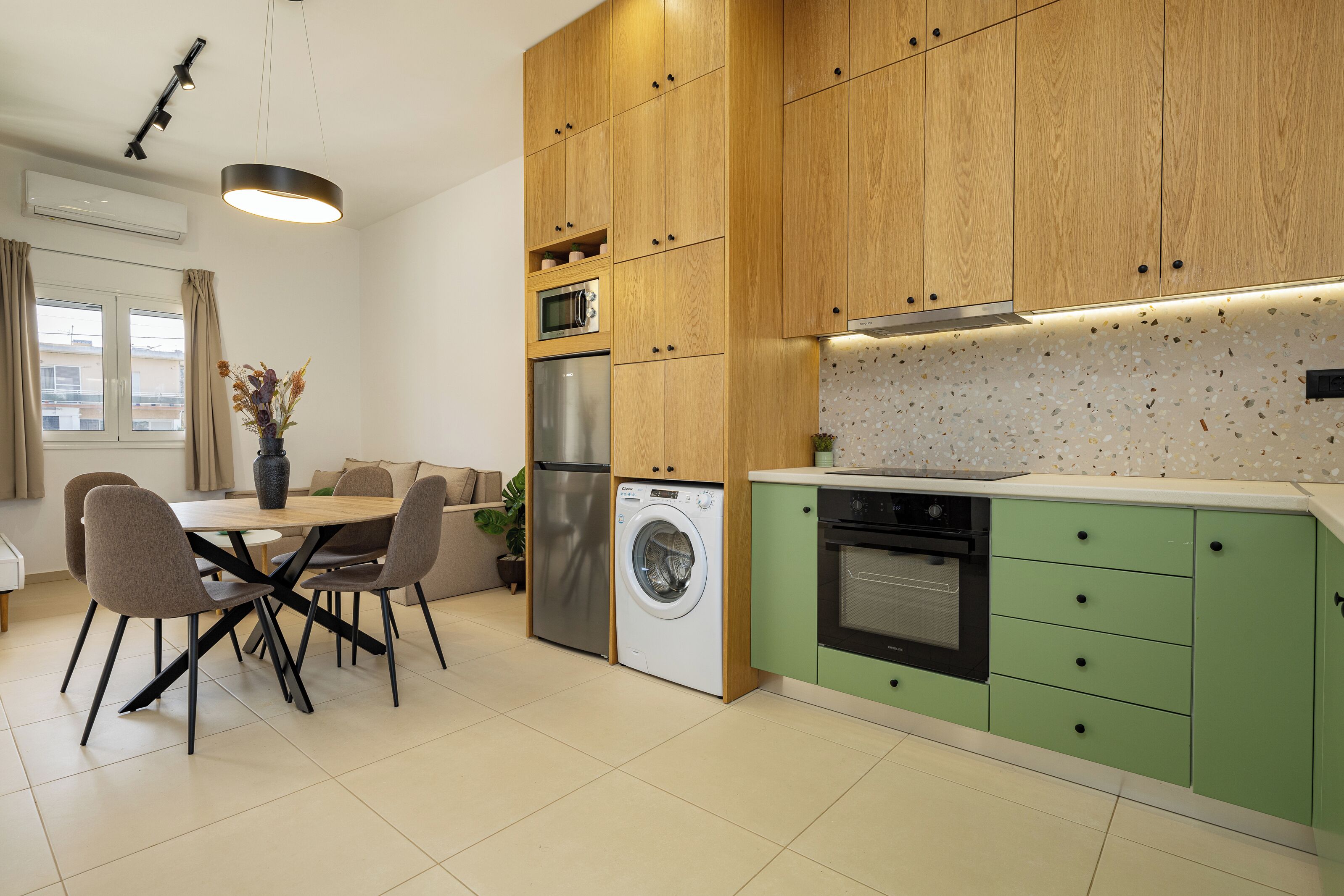 Eine moderne Küche mit Holzausstattung, einer Waschmaschine, einem Kühlschrank und einem Essbereich mit Tisch und Stühlen.