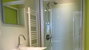 A modern bathroom with a white sink, mirror, and glass-enclosed shower.