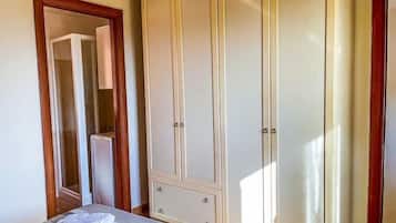 Un dormitorio con cama, armario y espejo.