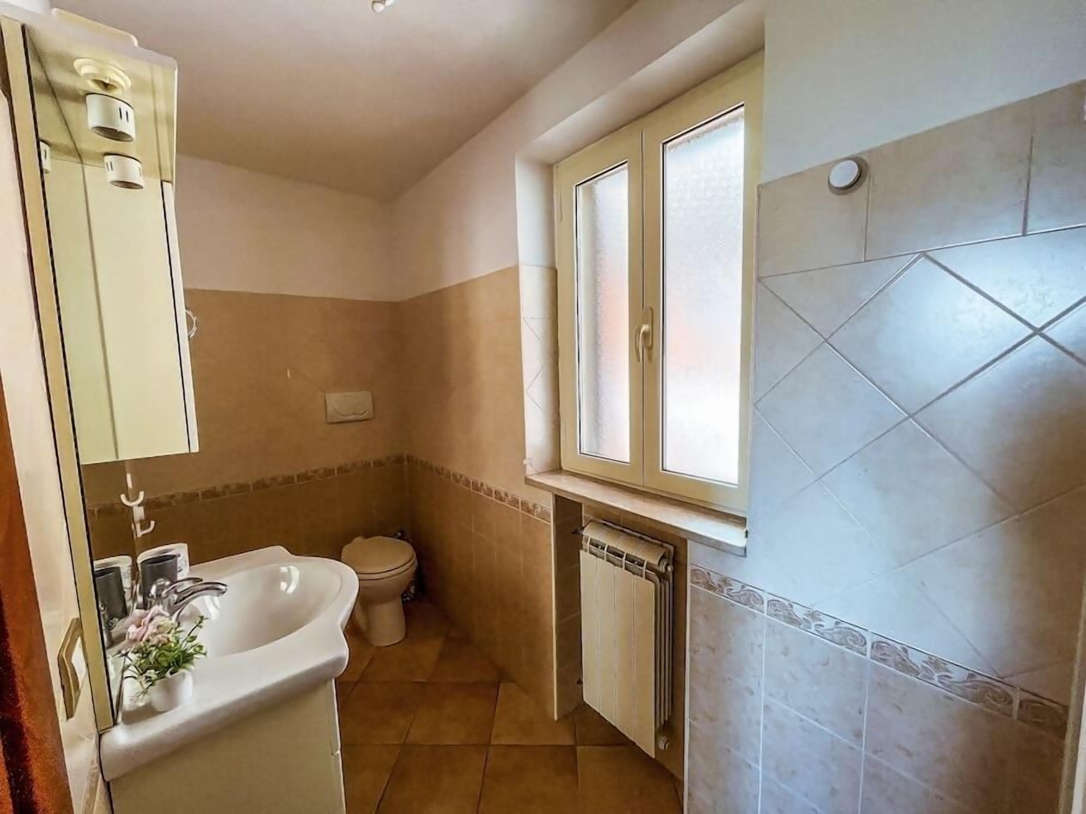 Un bagno con lavandino, wc e finestra.