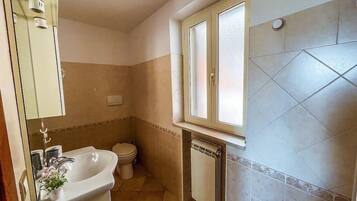 Un bagno con lavandino, wc e finestra.