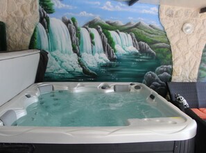 Un bain à remous avec une fresque représentant une cascade en arrière-plan.