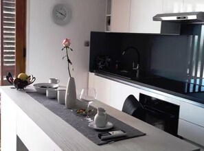 Eine moderne Küche mit einer schwarzen Dunstabzugshaube, einer Wanduhr und einem Essbereich mit einem Blumenstrauß.