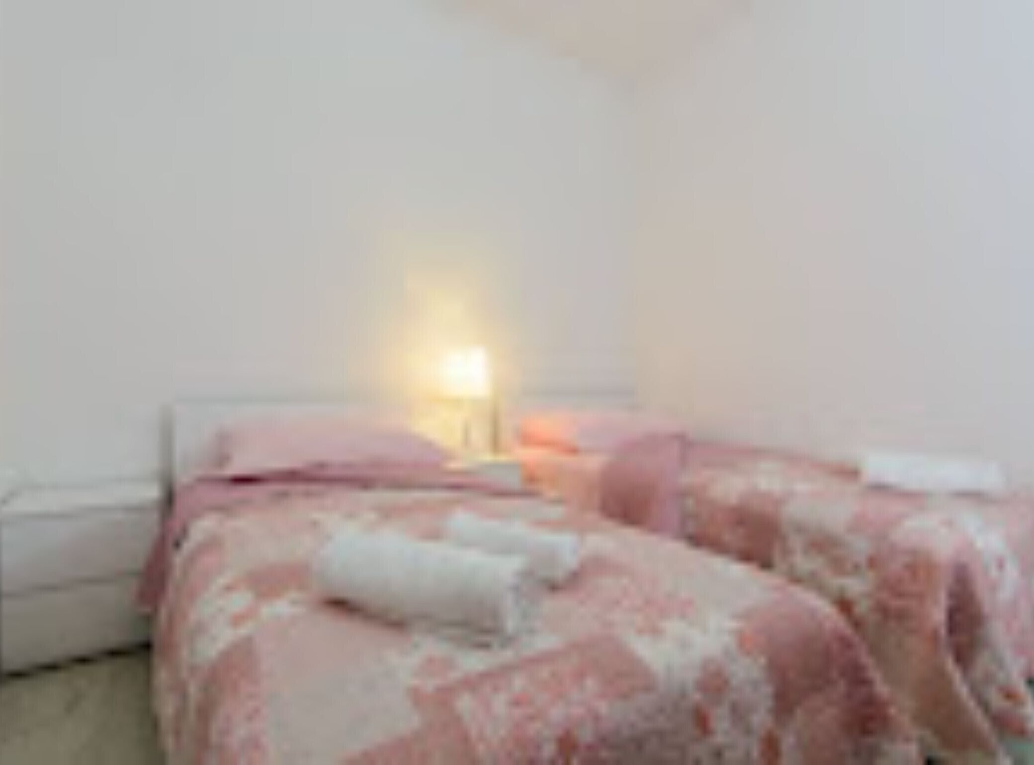 A bedroom with a bed, a bedside table, and a lamp.
