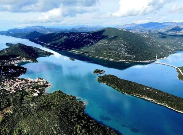 Vue aérienne d’une zone côtière avec un lac, entourée de montagnes et de petites îles.
