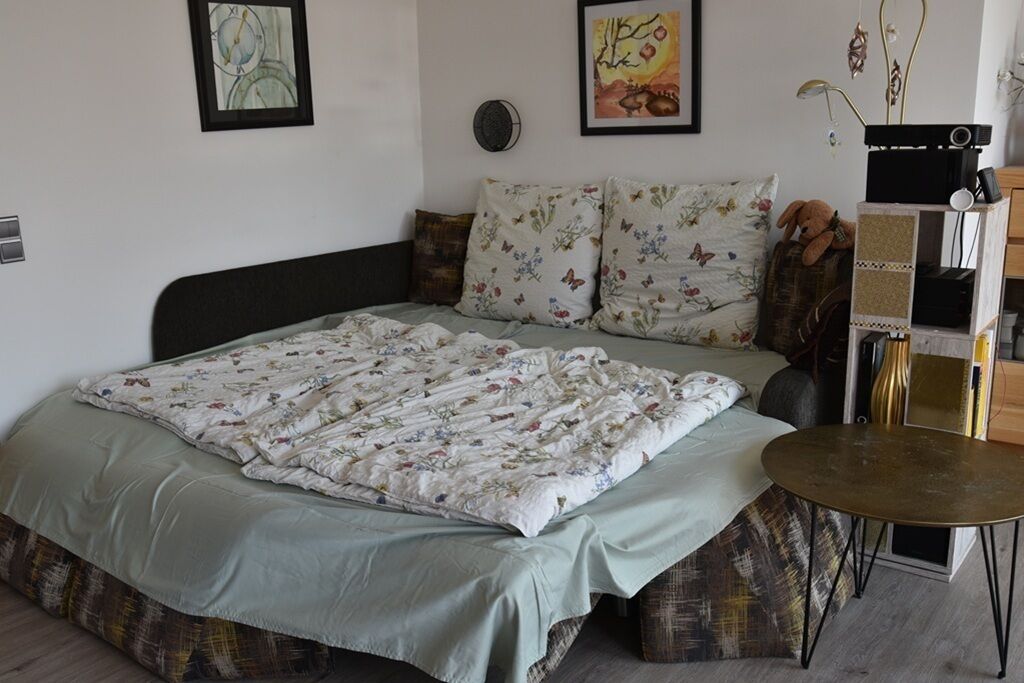 Un dormitorio con cama, almohadas, mesita de noche y decoración en la pared.