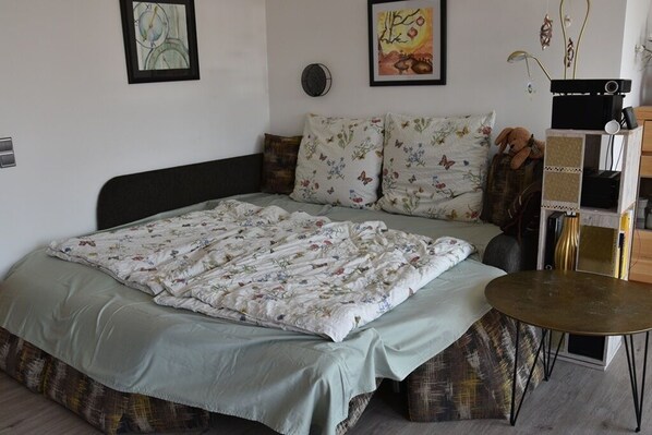 A bedroom with a bed, pillows, a bedside table, and wall art.
