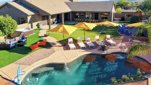 Un área de piscina con sillones de descanso, sombrillas y un jacuzzi.