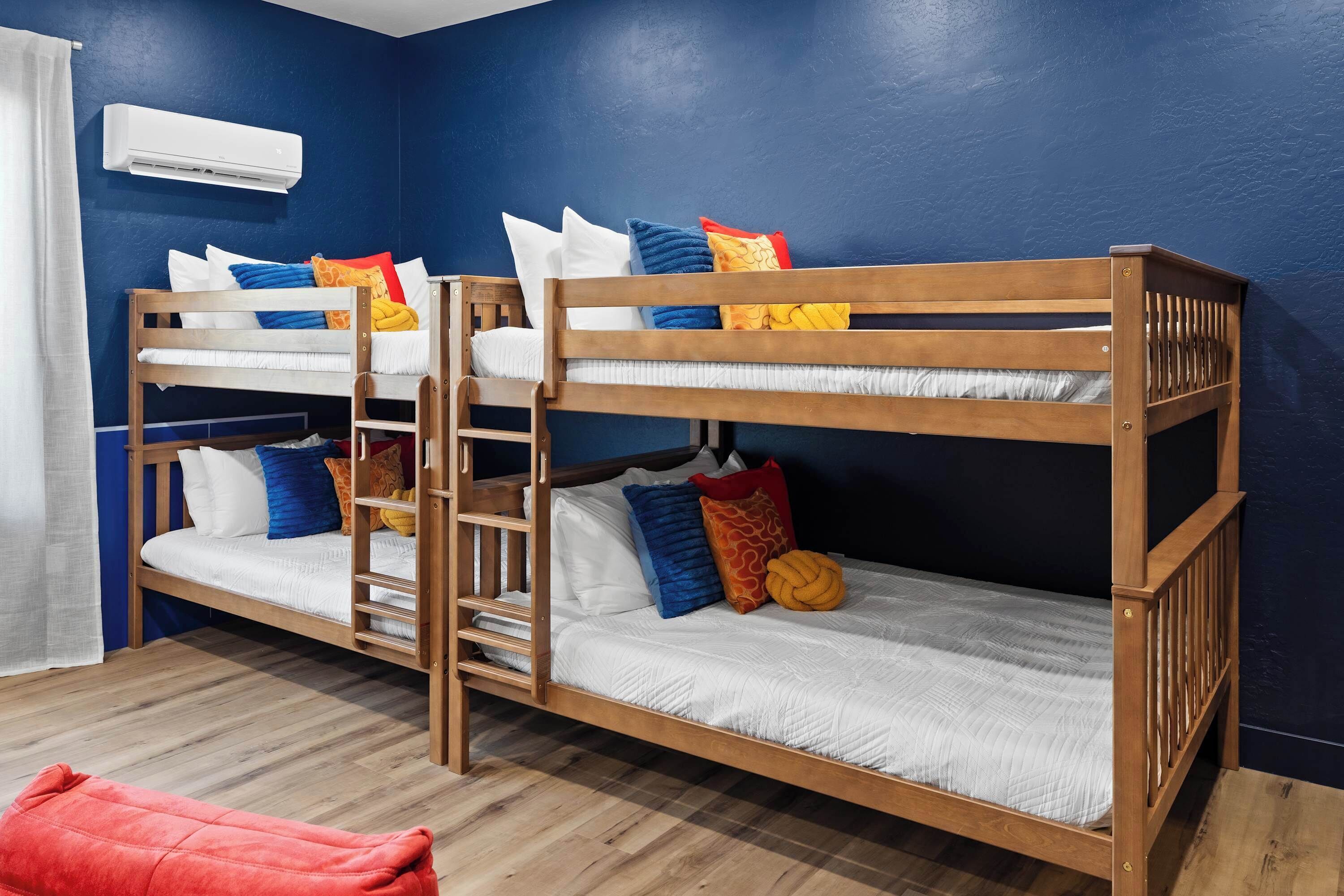 A bunk bed room with a ladder, white bedding, and colorful pillows.