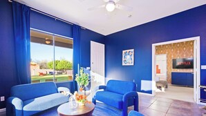 Una sala de estar con dos sofás azules, una mesa de centro y un televisor al fondo.