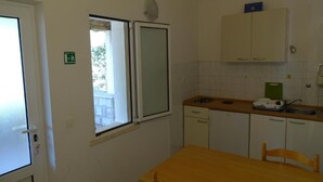 Eine kleine Küche mit Fenster, Tisch und Stuhl.