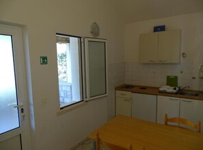 Eine kleine Küche mit Fenster, Tisch und Stuhl.