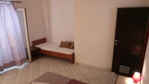 A small, simple room with a bed, a sofa bed, a door, and a window with curtains. - Villa Azure Saplunara - One bedroom apartment Mirta (Saplunara)
