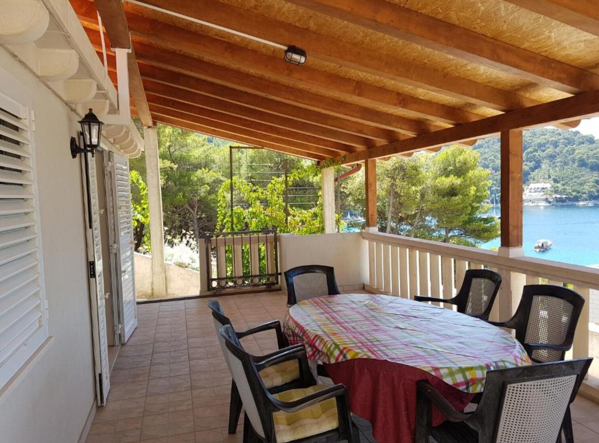 Un espace extérieur abrité, avec une table et des chaises, une vue sur la mer et un balcon doté d’une balustrade.