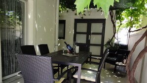Un'area pranzo all'aperto con tavolo, sedie, una bottiglia e un bicchiere.