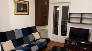 Ein Wohnzimmer mit einer Couch, einem Fernseher, einem Schrank und einer Glastür.