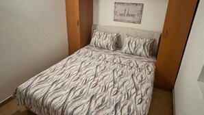 Ein Schlafzimmer mit einem Bett, einem Holzschrank und einem an der Wand befestigten Schild.
