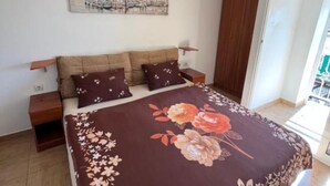Un dormitorio con una cama, dos mesitas de noche, un armario de madera y una obra de arte colgada en la pared.