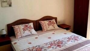 Ein Schlafzimmer mit einem Bett, zwei Kissen, einem Nachttisch, einer Lampe, einer Wand mit einem Zitat und einer Tür.