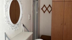 Ein Badezimmer mit weißem Waschtisch, einem Spiegel mit aufwendigem Rahmen, einem Holzschrank und einer geometrischen Wanddekoration.