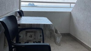Ein kleiner Balkon mit Tisch und Stühlen, Blick aufs Meer und einer strukturierten Wand.