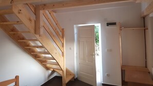 Eine Holztreppe führt zu einer Tür, einem kleinen Regal und einer weißen Wand.