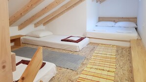 Ein kleines, gemütliches Schlafzimmer im Dachgeschoss mit schrägen Wänden, zwei Einzelbetten und einem Holzkopfstück.