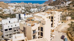 Un quartier résidentiel avec des immeubles modernes, une vue sur la mer et un paysage montagneux en arrière-plan.