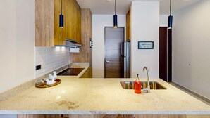 A modern kitchen with a granite countertop, stainless steel sink, and wooden cabinets. - Gorgeous & Spacious Apartment with Balcony, Heated Pool - AC (Cabo San Lucas)