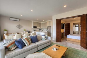 A modern living room with a sofa, coffee table, and dining area. - Peaceful coastal stay with pool, balcony & fitness center (Cabo San Lucas)