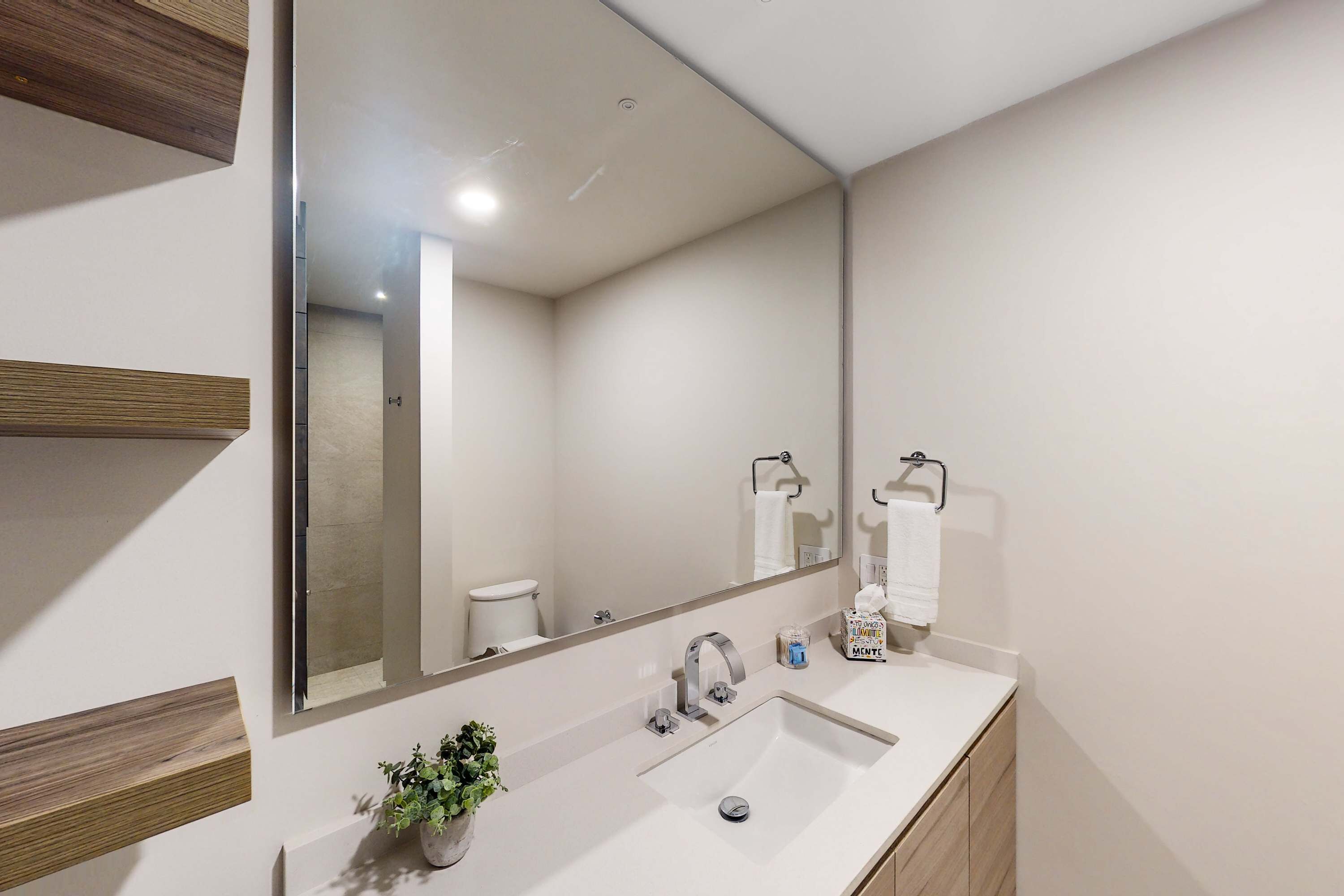 Une salle de bain moderne avec un grand miroir, un lavabo et des toilettes.
