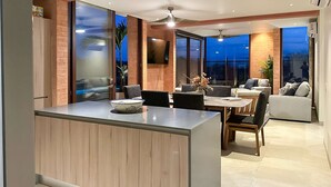Ein modernes Wohnzimmer mit Essbereich, großen Fenstern und einem Deckenventilator.