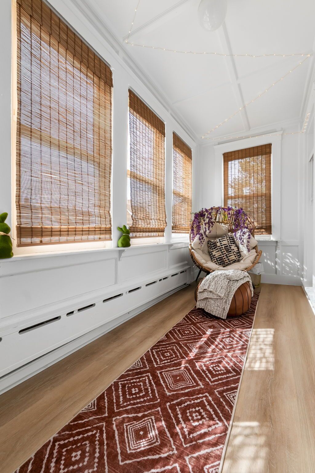 A room with large windows, a cushioned bench, a patterned rug, and a white radiator.