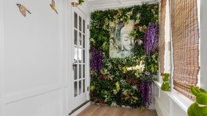 Un pasillo con un muro decorativo, una puerta y un ventanal con persianas.