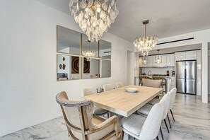 Ein moderner Essbereich mit Holztisch, gepolsterten Stühlen und einer Kronleuchter.