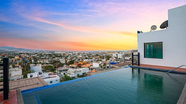 Une piscine à débordement située sur le toit, offrant une vue sur la ville, une antenne parabolique et une façade de bâtiment moderne.
