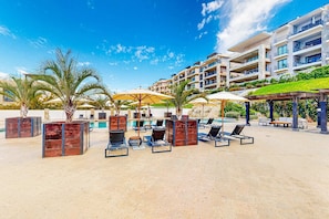 A resort with outdoor seating, palm trees, and a pool. - Ground-floor condo with ocean view, pool, gym, hot tub, & washer/dryer (Cabo San Lucas)