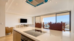 Een moderne keuken met een ingebouwde kookplaat, een flatscreen televisie en een groot raam met uitzicht op het landschap.