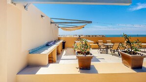 Eine Dachterrasse mit Sitzgelegenheiten im Freien, einem Billardtisch und Kübelpflanzen.