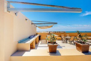 Eine Dachterrasse mit Sitzgelegenheiten im Freien, einem Billardtisch und Kübelpflanzen.