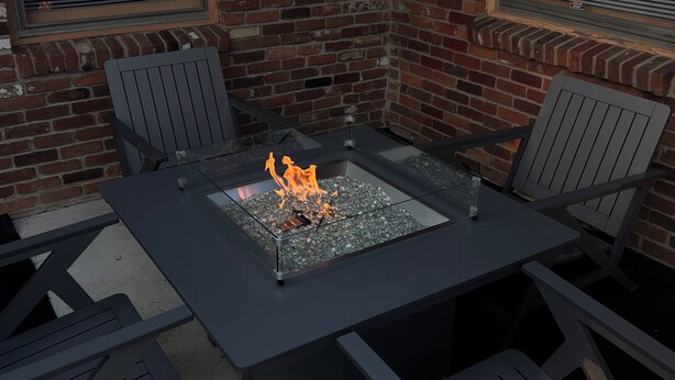 Un patio al aire libre con una chimenea, paredes de ladrillo y ventanas de estructura metálica.