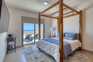 A bedroom with a four-poster bed, a large window, and a view of the sea. - Modern studio with rooftop lounge, pools, gym, pickleball & Netflix access (Cabo San Lucas)