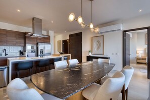 Een moderne keuken met een centraal eiland, roestvrijstalen apparatuur en een eethoek met een marmeren tafel.