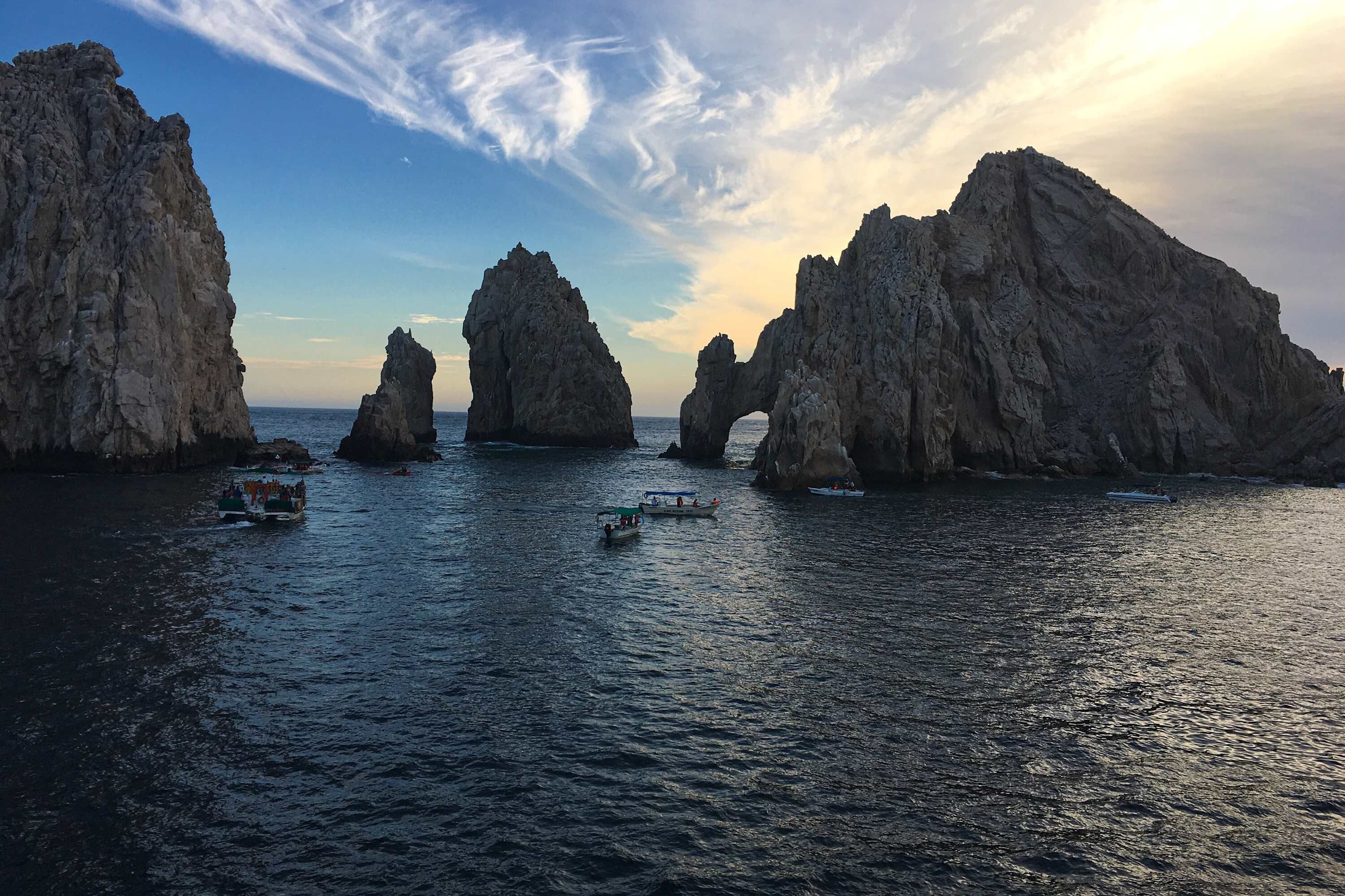 A coastal scene with large rock formations and boats on the water.