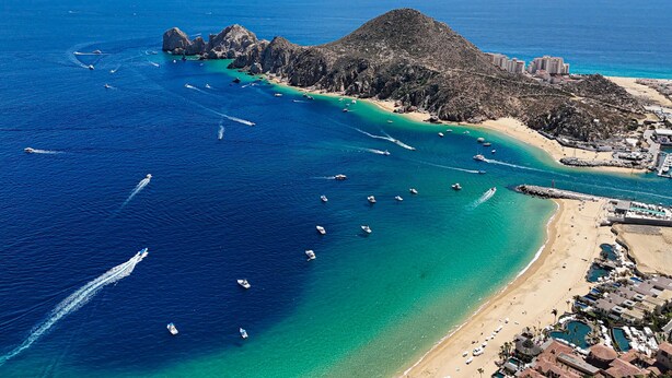 Vista aerea di una zona costiera con barche, una spiaggia e degli edifici.