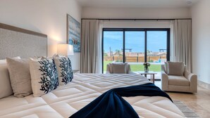 Camera d'albergo con un letto grande, vista sull'esterno, una sedia e un tavolo.